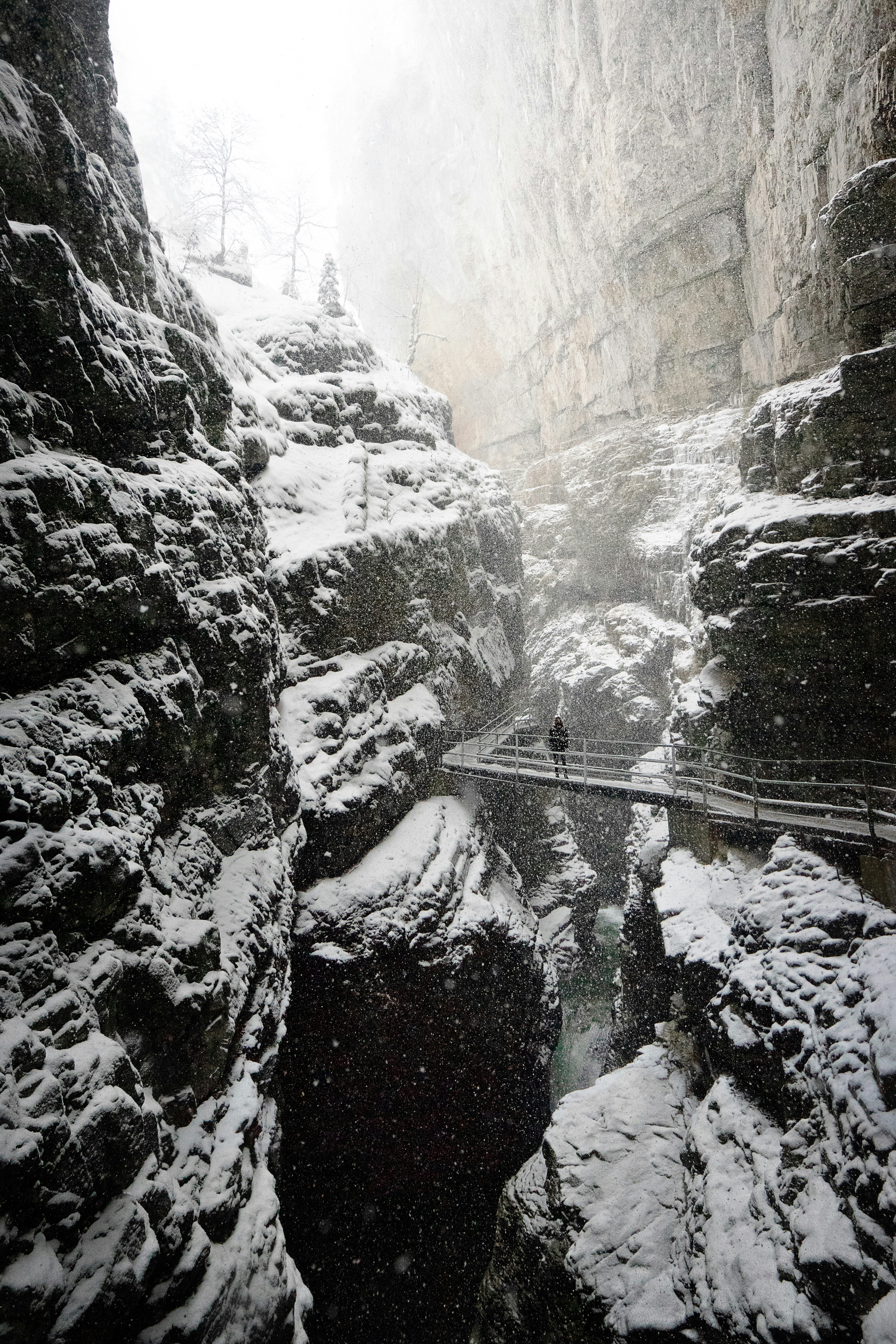 man standing on bridge in between rock formation